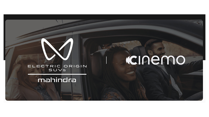 Cinemo and Mahindra logos on top of a brown-hued image of two people riding in a moving automobile.