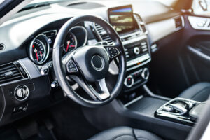 Interior view of a car with luxury steering wheel and clean dashboard with display.