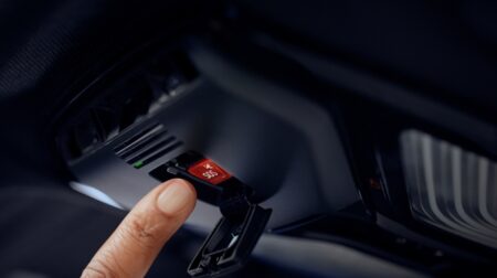 Harman introduces satellite voice calling to Ready Connect A finger moves toward a red SOS button in a vehicle display.