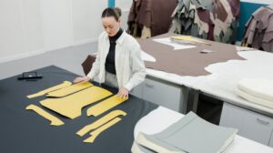 A worker at the new Scottish Leather Group Glasgow facility stands at a work table with a sustainable yellow material laid out in front of them.