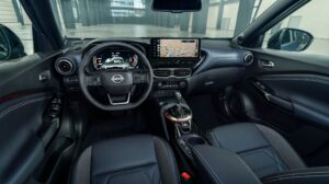 The dash and windshield of the Nissan Juke Pulse edition, with black seats and dash and a center console with touchscreen.