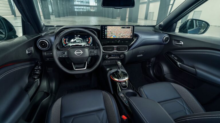 The dash and windshield of the Nissan Juke Pulse edition, with black seats and dash and a center console with touchscreen.
