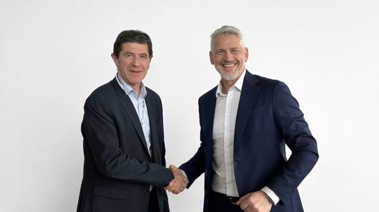 Marc Enjalbert, CEO of APEM, and Sascha Kunzmann, CEO of Alps Alpine in Europe, shake hands. They are both wearing dark suits and light shirts.