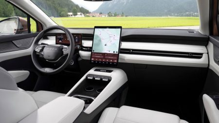 Skoda Peaq features vertically mounted display and Sonos premium sound system The interior of the Skoda Peaq, with light grey seating, dark blue dash and green grass visible through the windshield.